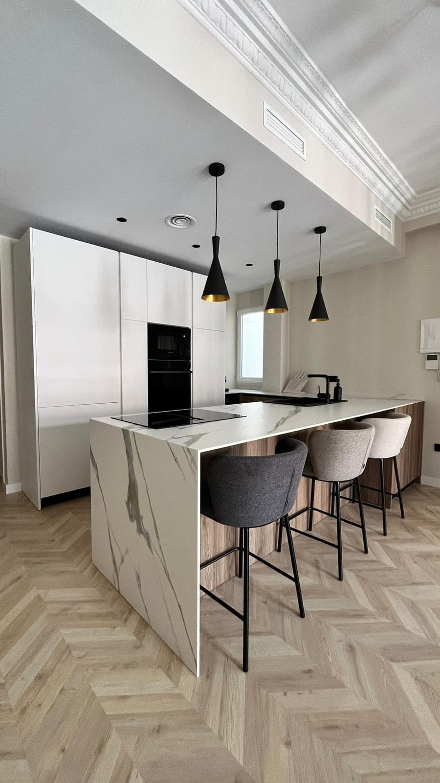 Cocina blanca con isla de acabado marmoleado y detalles en madera
