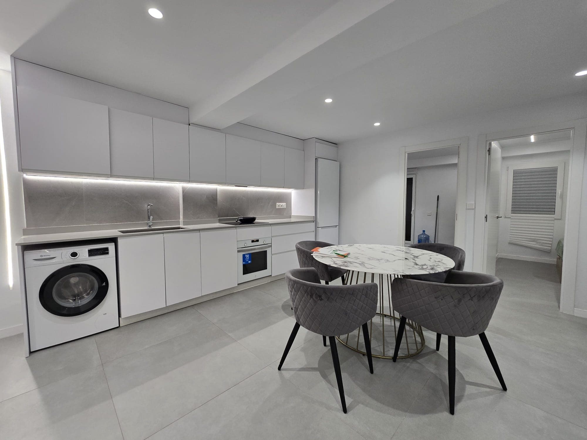 Cocina blanca de líneas rectas con iluminación integrada