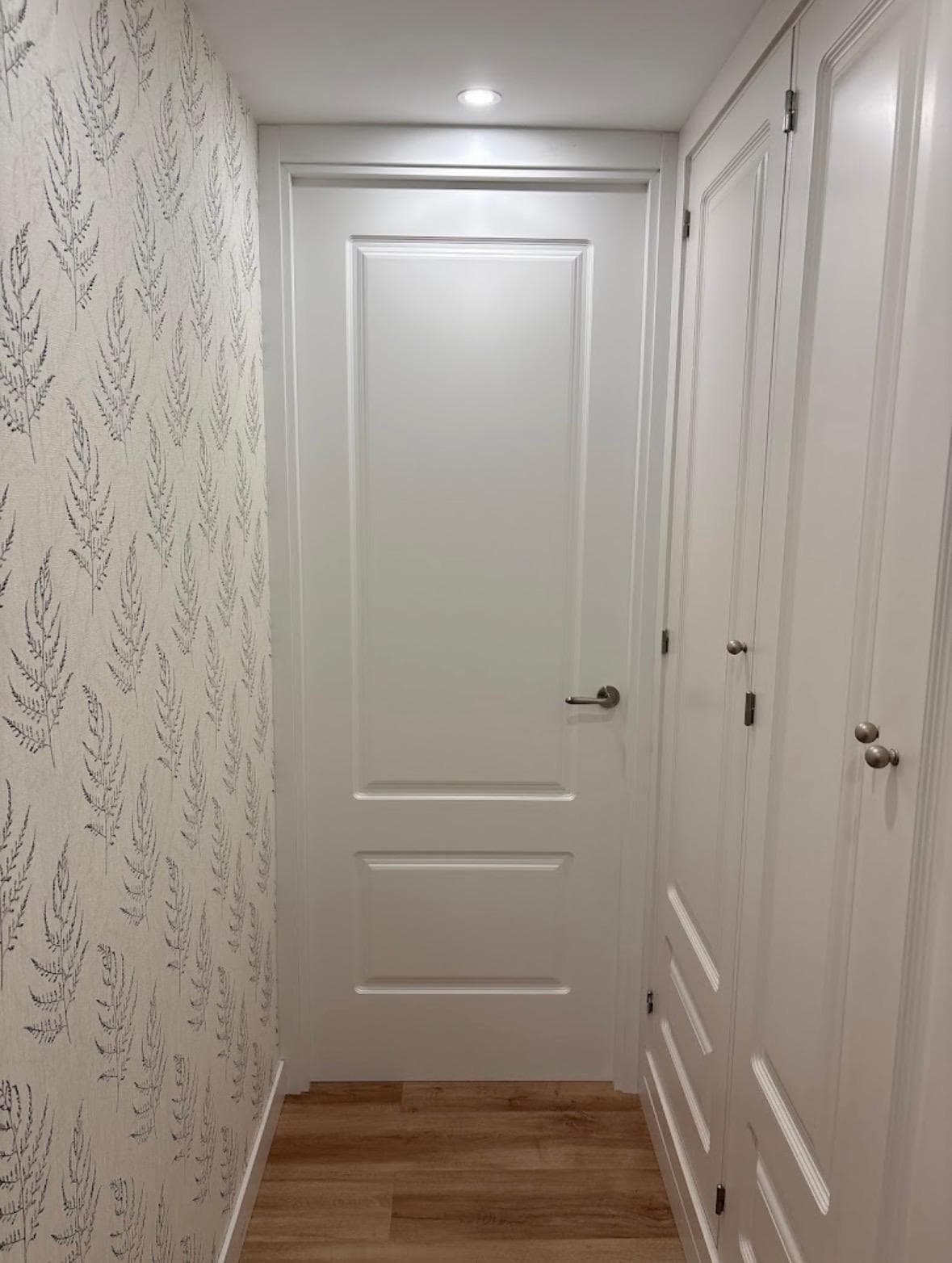Puertas blancas molduradas instaladas en un pasillo